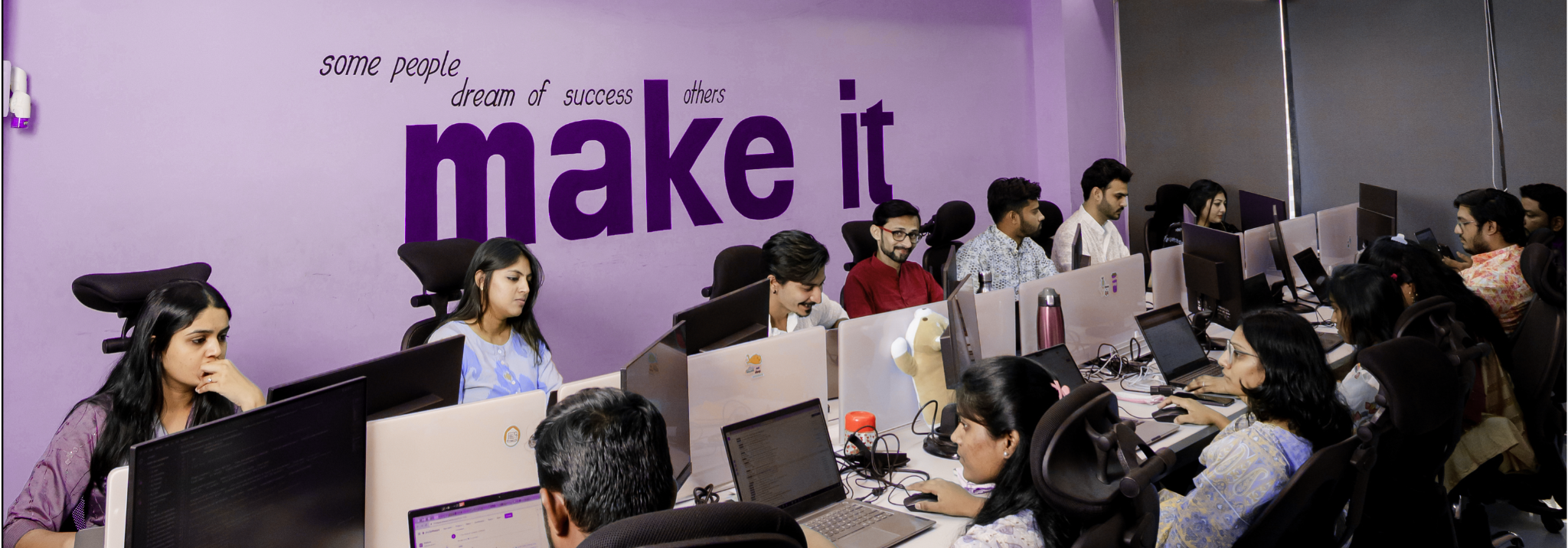 Calidad team working in modern office with motivational 'make it' wall text